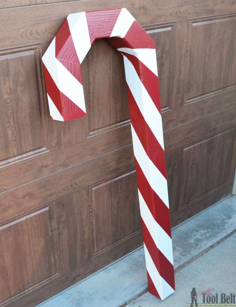 This is a perfect way to hang my Christmas stockings without a mantel! Free plans to build a DIY holiday Candy Cane stocking holder from a simple wood 4x4 post.