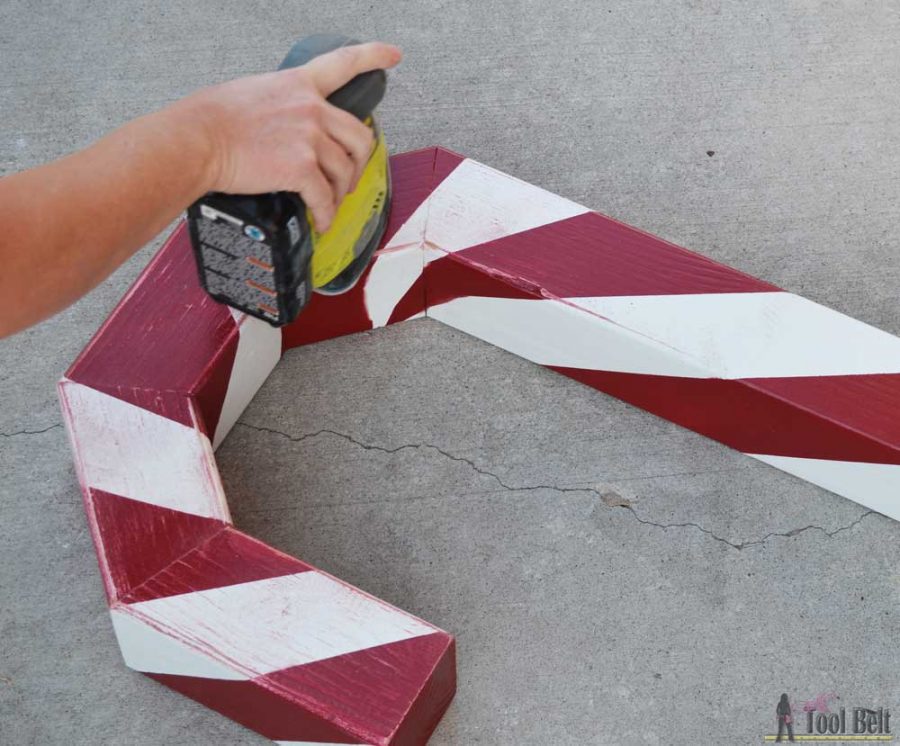 This is a perfect way to hang my Christmas stockings without a mantel! Free plans to build a DIY holiday Candy Cane stocking holder from a simple wood 4x4 post.