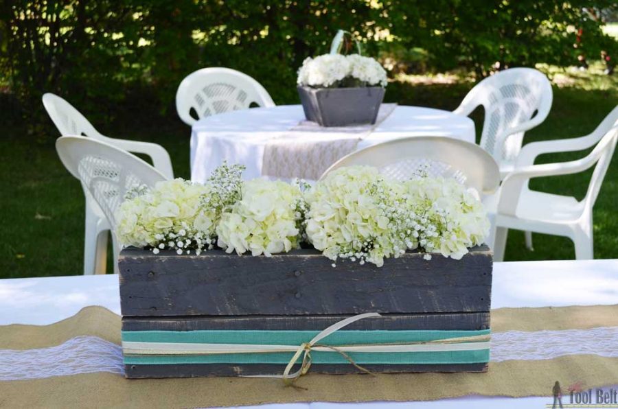 Gray planter box centerpiece with hydrangeas and baby's breath. Rustic DIY wedding decor.